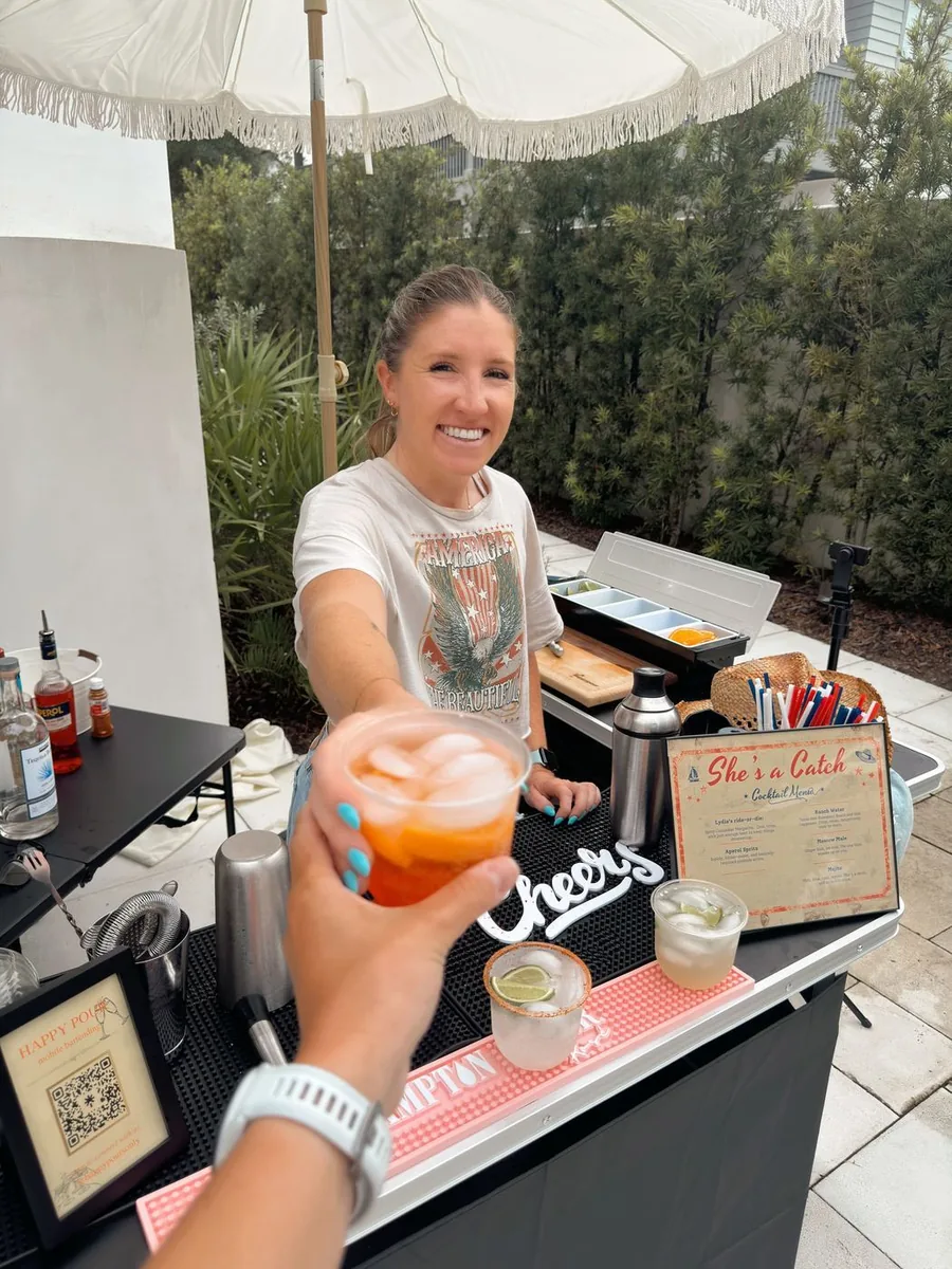 A Happy Pour bartender handing a spritz across the bar at an event