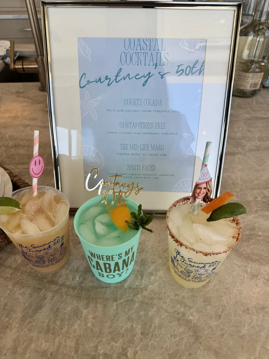 Three cocktails in custom party cups in front of a Coastal Cocktails menu