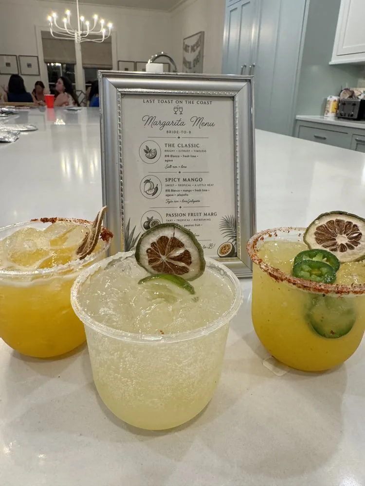Three margaritas with chili-salt rims and dried citrus in front of a custom margarita menu